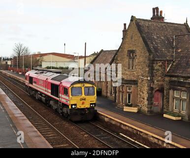 Pink Freightliner Diesel locomotive 66587 is passing through Burscough Bridge station on the Southport to Wigan railway line on a driver training trip Stock Photo