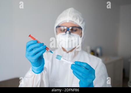 Medicine woman wearing protective gear, holding a test tube for 2019-nCoV analyzing. Coronavirus blood test concept Stock Photo