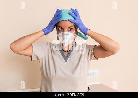 Healthcare worker girl is dressed in protective uniform, surgical cap, latex gloves and mask Stock Photo