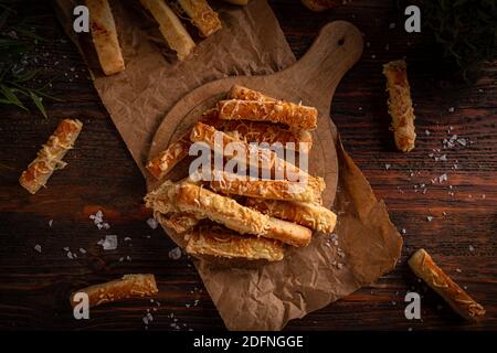Cheesy bread sticks on a cutting wooden board, top view, flat lay Stock Photo
