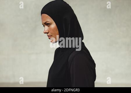 Close-up of muslim woman in sportswear outdoors. Female in hijab training outfit taking break after workout. Stock Photo