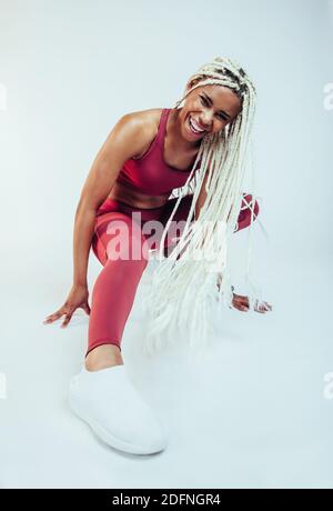 Close up of female athlete enjoying fitness training. African american fitness woman laughing during workout against white background. Stock Photo