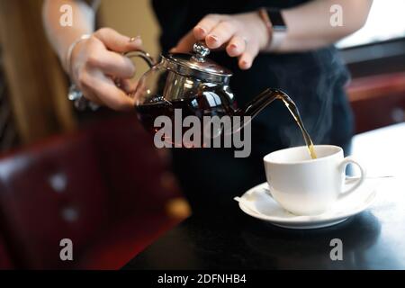 Waiter fills cup of tea in cafe Stock Photo