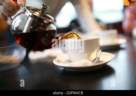 Person pouring tea into cup in cafe Stock Photo
