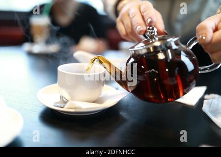 Waiter pouring tea into cup in cafe Stock Photo