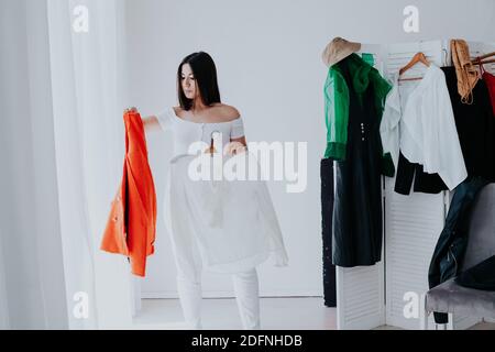 Portrait of happy young smiley brunette woman choosing outfit from wardrobe closet with stylish clothes Stock Photo