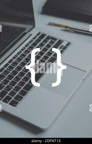 Coding and programming symbol on the background of a person typing on a laptop. Stock Photo