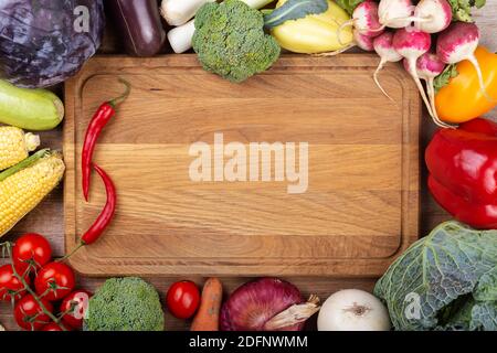 Exposition of fresh organic vegetables on a wooden table with space for text in the center. Healthy food -diet concept. Top view. Stock Photo
