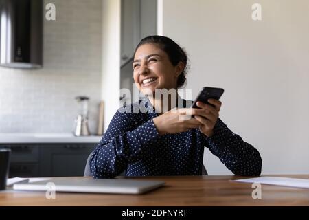 Overjoyed young indian woman holding cellphone laughing on internet joke Stock Photo