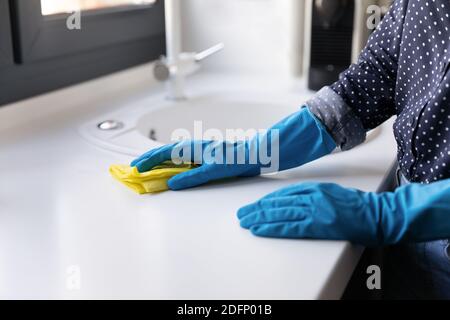 Female hands in rubber gloves cleaning kitchen counter with rag