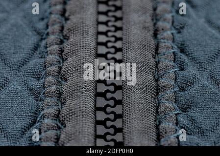 A macro shot of a closed, plastic zipper in a modern blue garment. Stock Photo