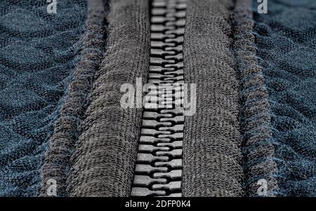 A macro shot of a closed, plastic zipper in a modern blue garment. Stock Photo