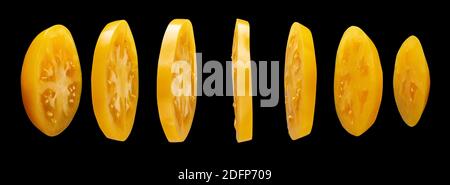 Yellow tomato slices levitating in the air on black background Stock Photo