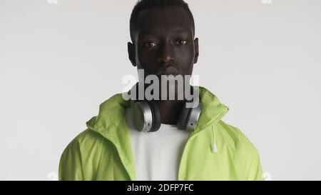 Stylish African American guy in bright jacket with headphones looking serious in camera isolated on white background Stock Photo