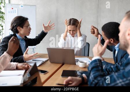 Business People Having Conflict Shouting At Unhappy Businesswoman At Workplace Stock Photo