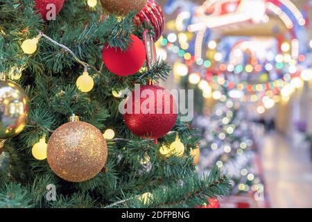 Christmas tree with red and gold balls on the background of bokeh from multi-colored garlands. Stock Photo
