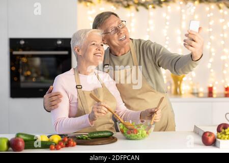 Elderly Couple Making Selfie Having Fun Celebrating Christmas At Home Stock Photo