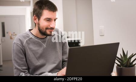 Man smiling and working at home on laptop computer. Stock Photo