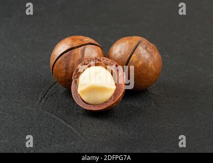 Three macadamia nuts on a dark concrete background Stock Photo