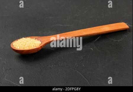 Wooden spoon with brown sugar on a dark background Stock Photo