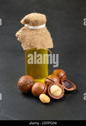 Oil in a bottle with macadamia nuts on a dark background Stock Photo