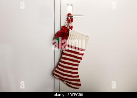 Christmas sock with red stripes for Christmas gifts hanging on the door. Holiday symbol stocking. Stock Photo