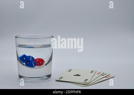 glass of alcohol containing red and blue dice with perfect four aces on white background Stock Photo