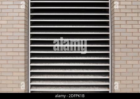 Exterior light colored brick wall with inset industrial vent, urban commercial building details, horizontal aspect Stock Photo