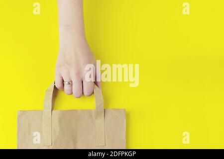 Brown clear empty blank craft paper bag for takeaway on the yellow background. Packaging template mockup. Delivery service concept. Copy space Adverti Stock Photo