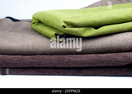 Folded pieces of fabric on a white background. Green and brown fabric for upholstery. Convolutions of fabric stacked on top of each other. Stock Photo