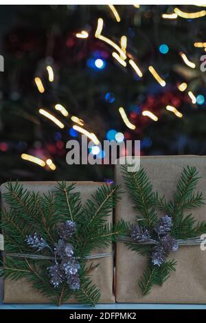 Gift boxes and christmas decorations under a beautiful decorated christmas tree with bokeh lights. Christmas gift box in front of christmas tree. Stock Photo