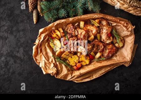 Dish for Christmas, baked rabbit meat with vegetables close-up on baking paper on the table. Top view. Space for text Stock Photo