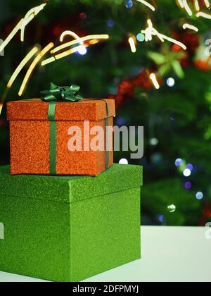 Gift boxes and christmas decorations under a beautiful decorated christmas tree with bokeh lights. Christmas gift box in front of christmas tree. Stock Photo