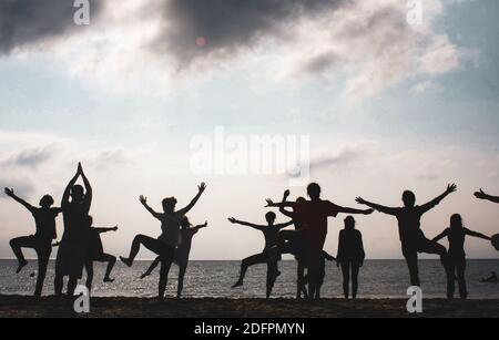 People are silhouetted on the beach doing physical exercises during a summer day. Stock Photo