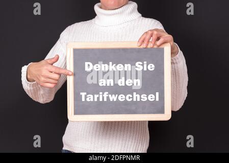 A man holding a chalkboard with 'think about the tariff change' written on it Stock Photo