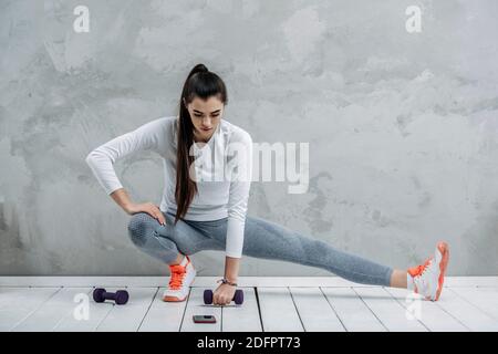 Fitness girl training isolated on grey background. A sports coach leads an online lesson. Online workout concept Stock Photo