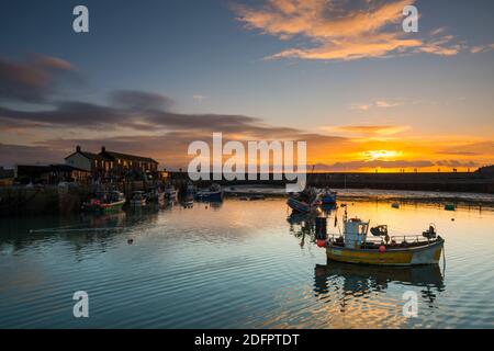 Lyme Regis, Dorset, UK.  6th December 2020.  UK Weather.  The sky glows orange at sunset at the Cobb Harbour at Lyme Regis in Dorset at the end of a cold day with sunny spells.  Picture Credit: Graham Hunt/Alamy Live News Stock Photo