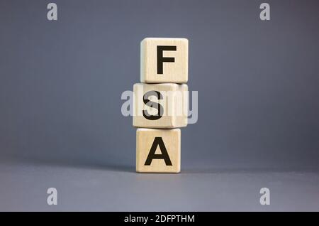 FSA symbol. Concept word 'FSA, flexible spending account' on cubes on a beautiful grey background. Business and FSA concept. Copy space. Stock Photo