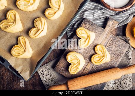 Raw unbaked homemade sweet buns with honey and sugar on rustic plywood background. Preparation for baking. Top view. Stock Photo