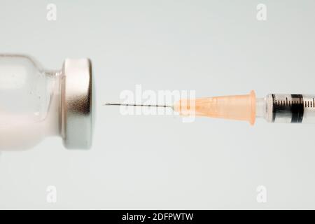 Vaccine vial with vaccination syringe, orange cannula and white background. Macro Stock Photo