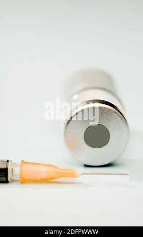 orange cannula syringe with vaccine in vial, blue background Stock Photo