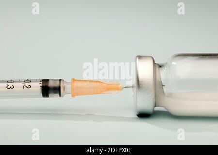 Vaccine vial with vaccination syringe, orange cannula and white background. Macro Stock Photo