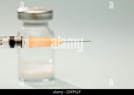 orange cannula syringe with vaccine in vial, blue background Stock Photo