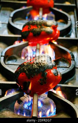 preparation of Roasted red peppers on direct flames in a kitchen Stock Photo