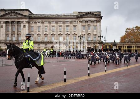 A policeman on a horse leads the soldiers wearing  Bearskins and grey long coats during the changing of the guard parade at Buckingham Palace, London. Stock Photo