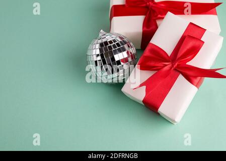 Boxing Day Sale concept with gift box tight with silk red bow and golden balls against turquoise green background, top view and empty copy space. Stock Photo