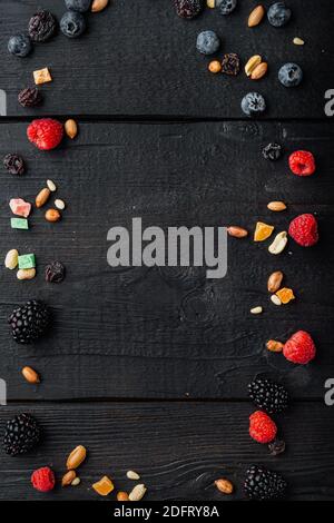 Frame made of mixed dried and raw ripe berry and fruit with nuts, top view with copy space, on black wooden table Stock Photo