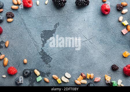 Frame made of mixed dried and raw ripe berry and fruit with nuts, flat lay with space for text, on grey background Stock Photo