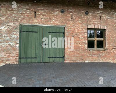a green large door and a rectangular low window on a brick wall building Stock Photo