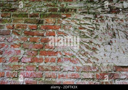 vintage cracked dirty brick wall with peeling plaster prepared for restoration, texture, background Stock Photo